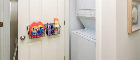 Un cuarto de lavandería con una lavadora blanca y una puerta con dos cestos para detergente.