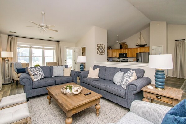 A living room with two sofas, a coffee table, and a kitchen in the background.