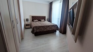 A hotel room with a large bed, a nightstand, a lamp, a TV, and a wardrobe. - Luxuriöse Ferienwohnung im Harmony Suites Monte Carlo am Sonnenstrand (Sonnenstrand)