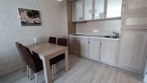 A compact kitchen with a dining table, chairs, and cabinets. - Luxuriöse Ferienwohnung im Harmony Suites Monte Carlo am Sonnenstrand (Sonnenstrand)