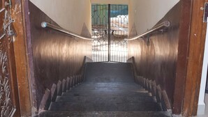 Una escala amb barana metàl·lica, una porta de fusta a l'esquerra i una finestra a la part superior.