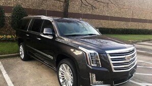 A black Cadillac SUV parked in a lot with a building in the background.