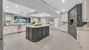 A spacious kitchen with a large island, white cabinetry, and a stone accent wall.