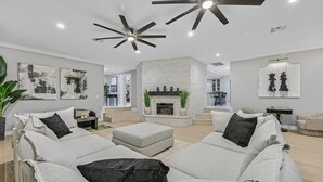 A spacious living room with a fireplace, ceiling fans, and modern furniture.