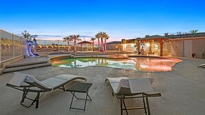 A pool area with lounge chairs, a gazebo, and a covered seating area.