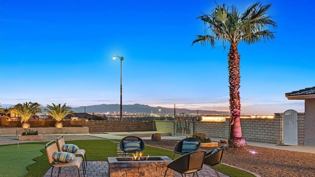 A patio with a fire pit, outdoor furniture, and a palm tree.