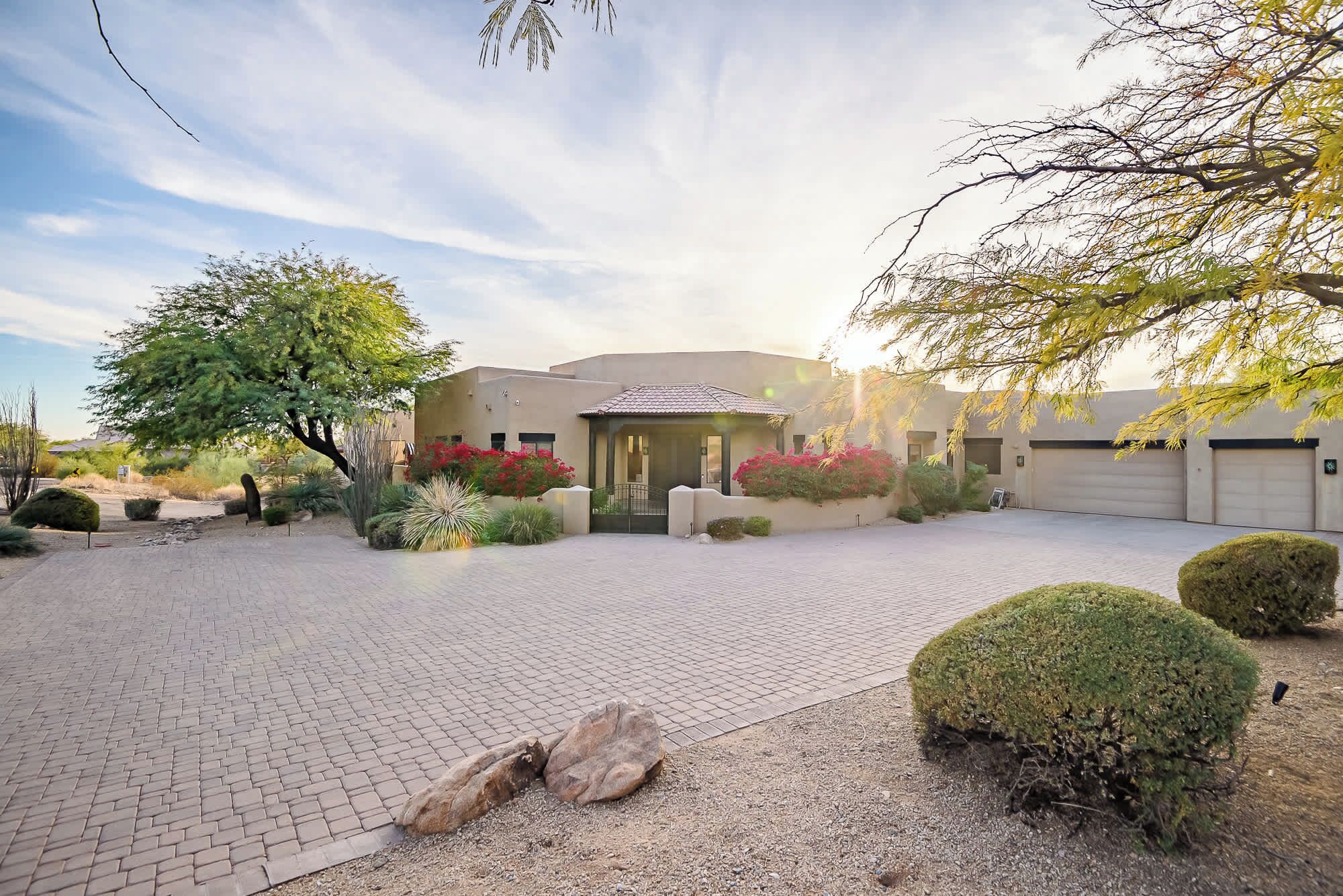 A modern building with a paved driveway, a covered entrance, and landscaped gardens.