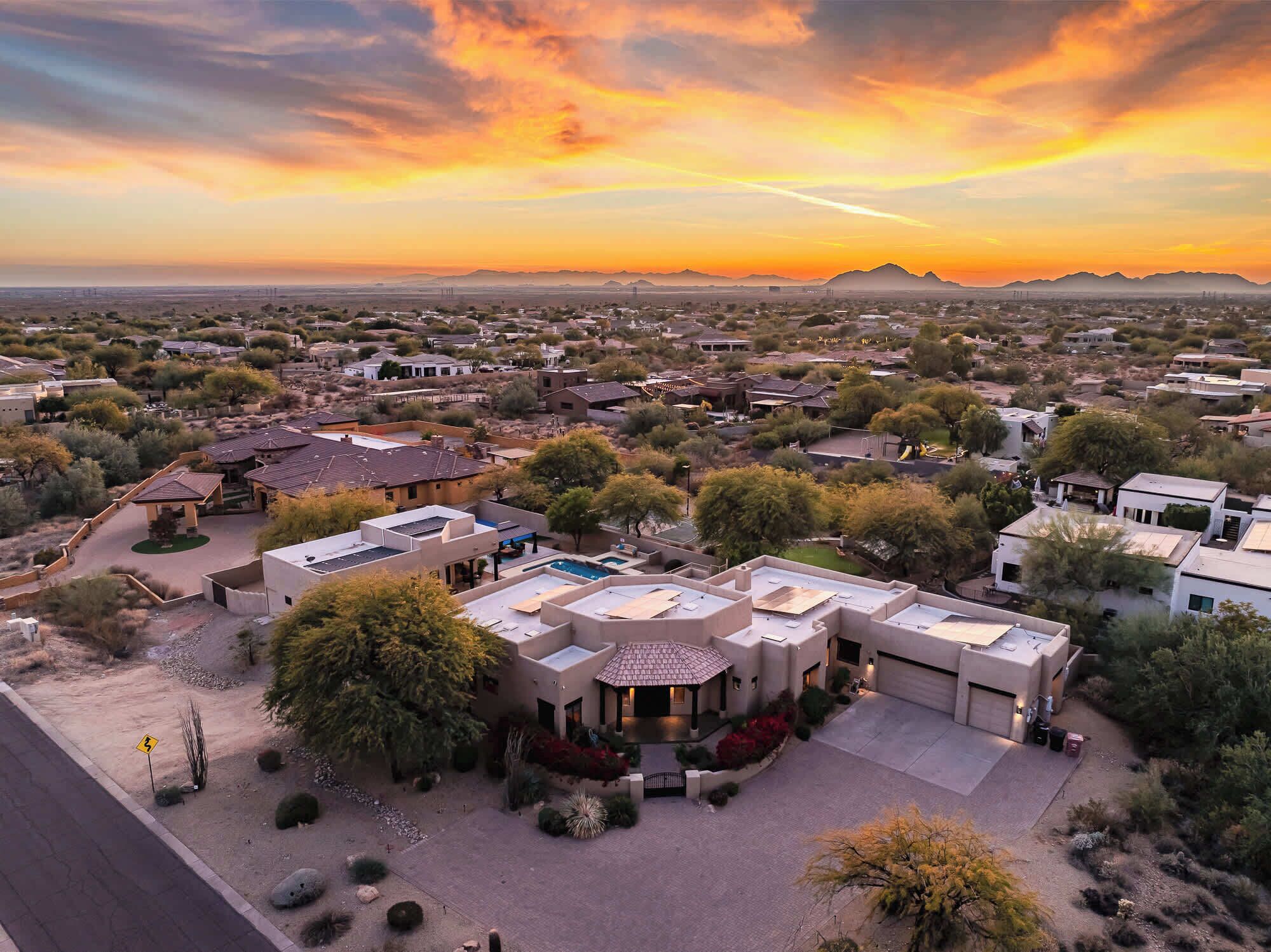 Vista aérea de una zona residencial con casas, una piscina y un edificio grande con techo plano.