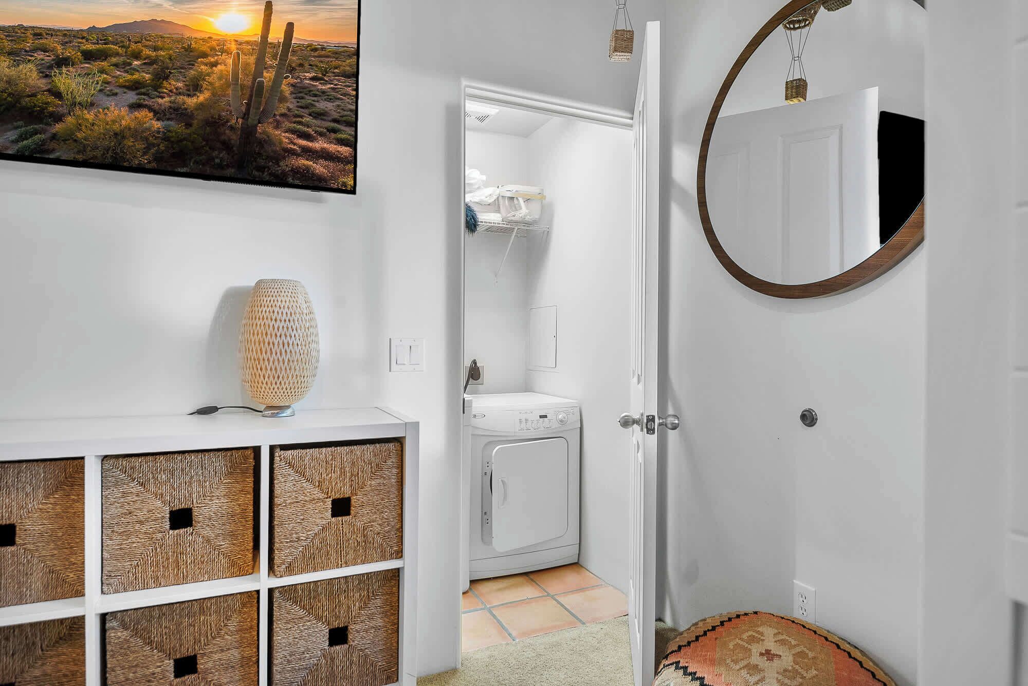 Une salle de bain équipée d’un lave-linge, d’un miroir et d’un élément décoratif mural.