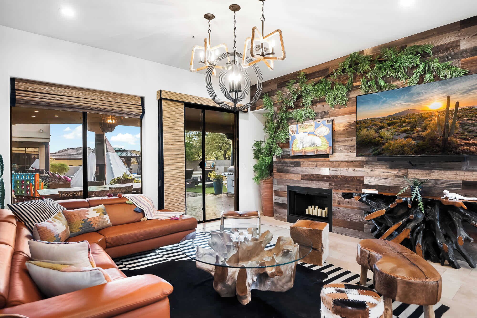 Una sala de estar moderna con sofás de cuero, una mesa de centro de vidrio, una chimenea y un ventanal con vistas a un jardín.
