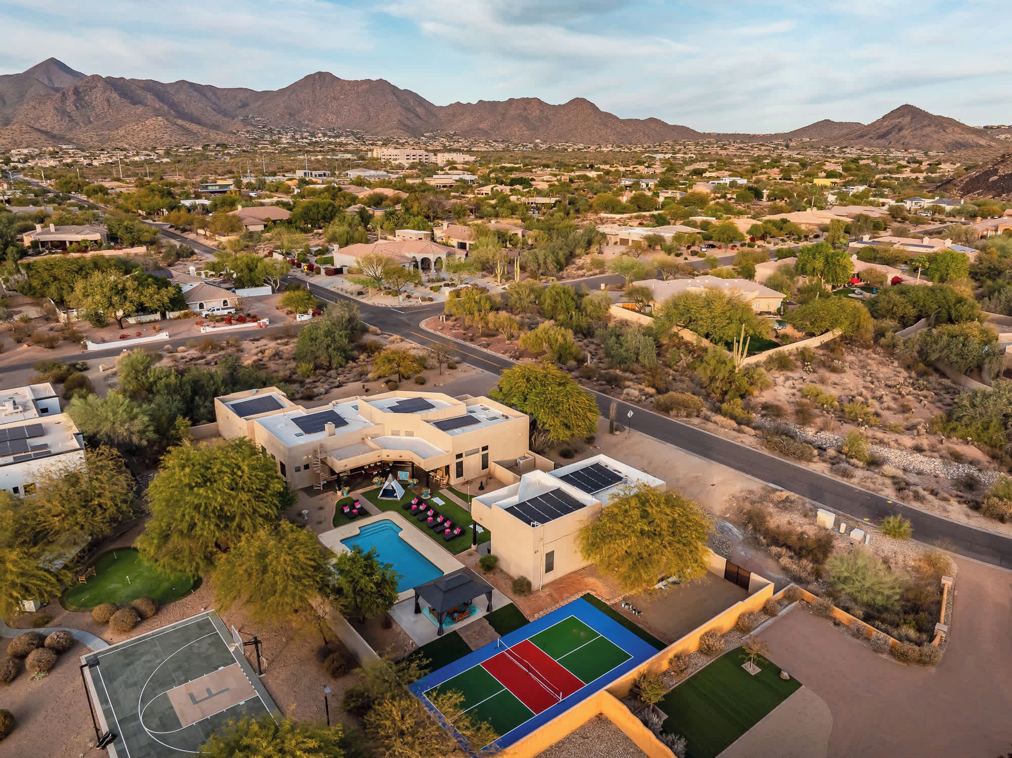 An aerial view of a residential area with houses, a swimming pool, and a tennis court.