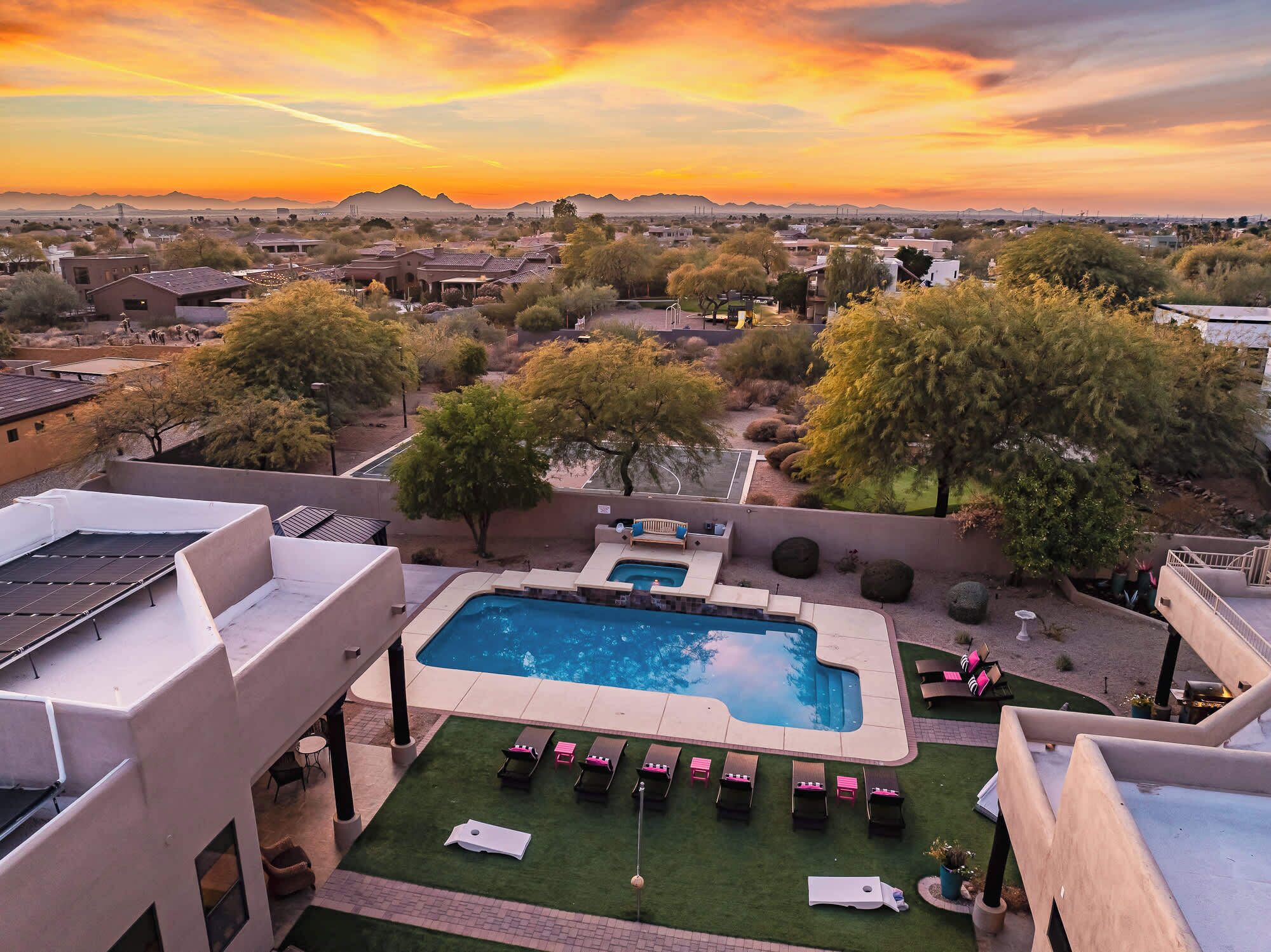 A rooftop pool with lounge chairs and a view of the surrounding landscape during sunset.