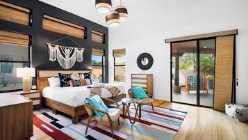 Habitación de hotel moderna con una cama grande, un escritorio, una silla, una alfombra colorida y vistas al exterior a través de una puerta corredera.