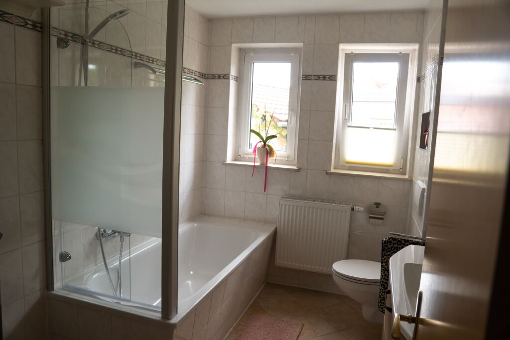 Un bagno con doccia vetrata, vasca da bagno, servizi igienici e una finestra con una pianta.