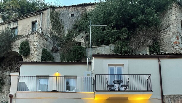 A multi-story building with balconies, outdoor lighting, and a stone facade.