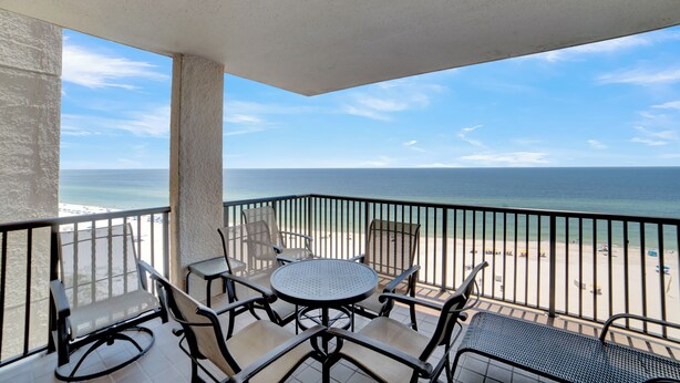 A balcony with a view of the beach and ocean.