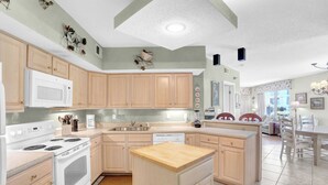 A kitchen with wooden cabinets, a white stove, a microwave, and a wooden island.