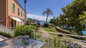 A terrace with a table set for tea, overlooking a scenic view of the sea and a garden with a pathway leading to a building. - Paradise Corner by Interhome (Ventimiglia)
