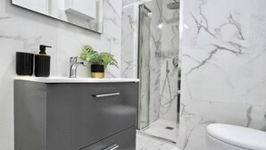 A modern bathroom with a marble sink, a shower, and a toilet.