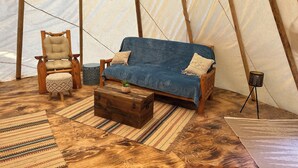 En ombonad inredning med en soffa i trä, en bekväm fåtölj, ett litet bord och en förvaringskista.