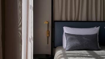 Een hotelkamer met een bed, nachtkastje, lamp en raam met gordijnen.