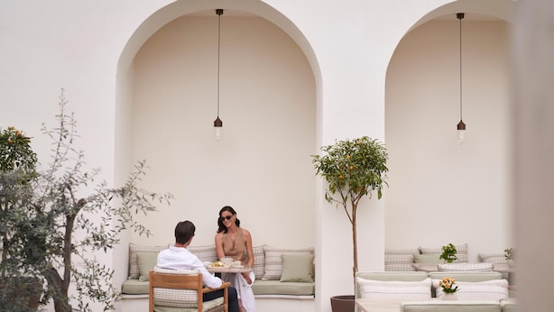 A serene outdoor seating area with a wooden table, two cushioned sofas, and a potted plant. - Amyth of Nicosia (Nicosia)