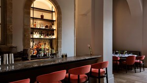 A bar area with a marble countertop, red bar stools, and a wine rack with various bottles. - Amyth of Nicosia (Nicosia)