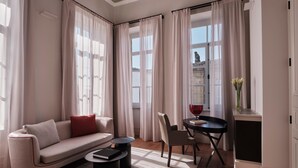 A modern living room with a sofa, two side tables, a chair, a small table with a vase, and a window with curtains. - Amyth of Nicosia (Nicosia)