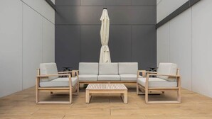 Un área de estar moderna con un conjunto de sofás, dos sillones y una mesa de centro de madera.