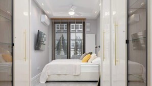 Un dormitorio moderno con cama, ventilador de techo y ventana con persianas.