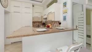 A modern kitchen with a central island, white cabinetry, and a clock on the wall.