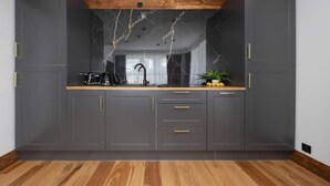 Una cocina moderna con armarios gris oscuro, encimera de madera y salpicadero de mármol.