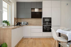 Une cuisine moderne dotée d’un plan de travail en bois, d’appareils électroménagers intégrés et d’un coin repas avec une table et des chaises.