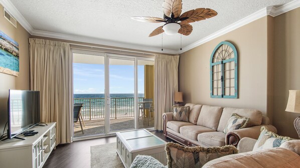 A spacious living room with a large sliding glass door leading to a balcony with a view of the ocean. - Emerald Isle 404 - Affordable rates!! (Panama City Beach)