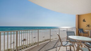 Un balcón con vista a la playa, una mesa, sillas y detalles decorativos en la pared.