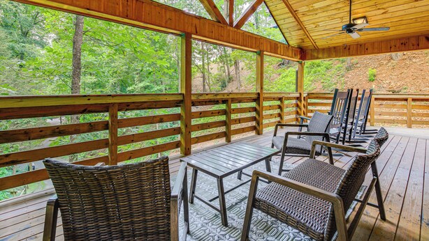A covered deck with wooden railings, wicker furniture, and a ceiling fan. - 2 Mi to Dtwn Gatlinburg: 'crescent Claw Cabin!' (Gatlinburg)