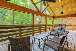 A covered deck with wooden railings, wicker furniture, and a ceiling fan. - 2 Mi to Dtwn Gatlinburg: 'crescent Claw Cabin!' (Gatlinburg)