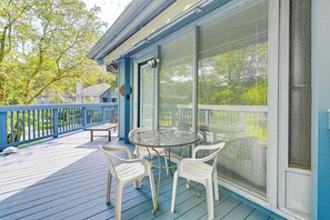 Relax on the deck with a round table and four chairs, surrounded by lush greenery and a large window with a view.
