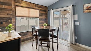 En matplats med ett träbord och stolar, en krukväxt och utsikt genom en skjutdörr i glas.