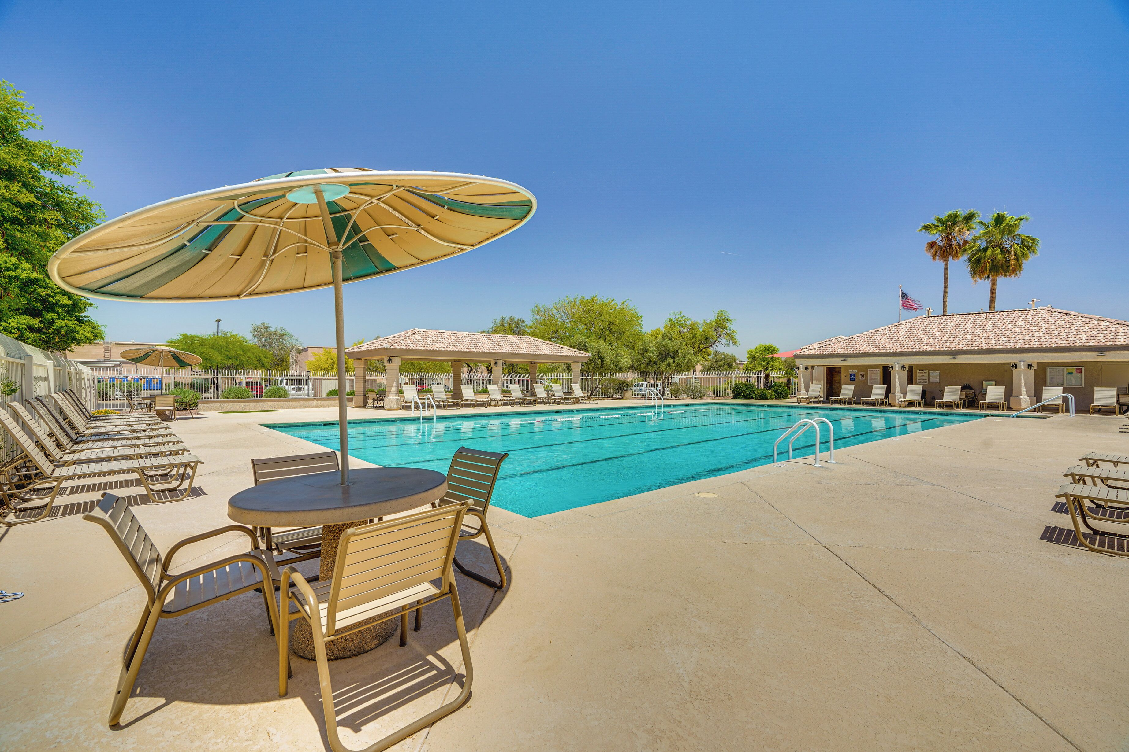 A pool area with lounge chairs, a table, and umbrellas.