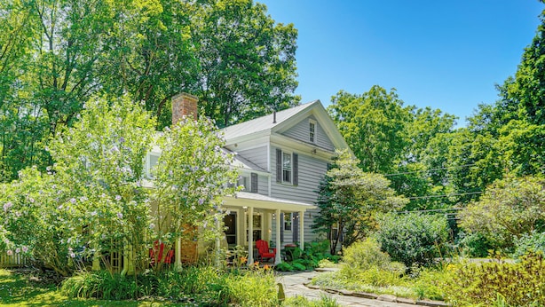 A two-story house with a covered porch and a garden.