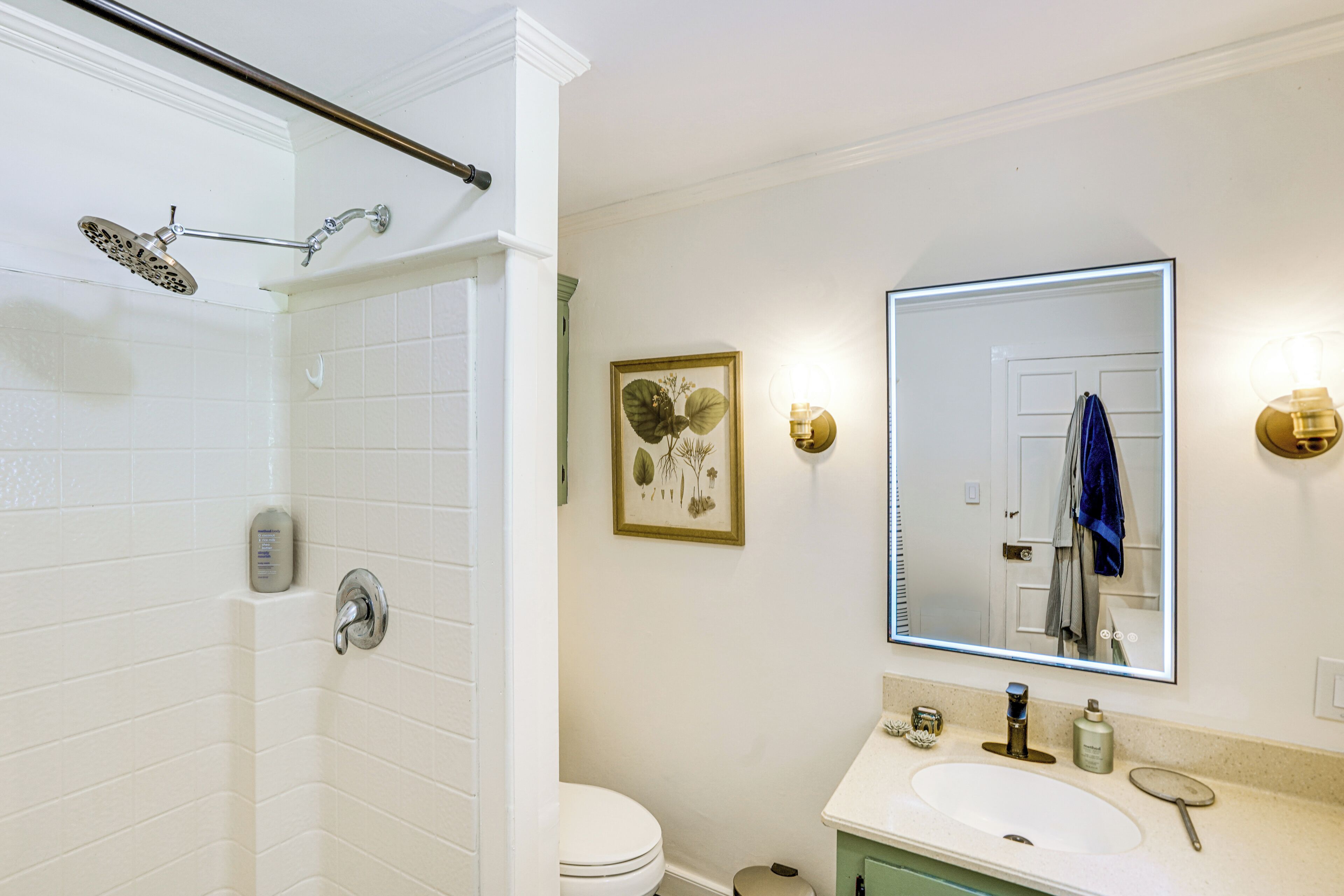 Une salle de bain équipée d’une douche, de toilettes, d’un lavabo et d’un grand miroir.
