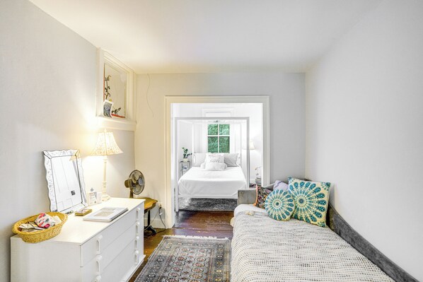 Une chambre à coucher avec un lit, une commode, un miroir, une lampe et une fenêtre.