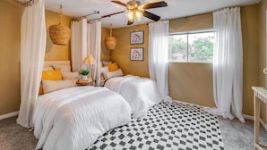A bedroom with two beds, a ceiling fan, and a large window with curtains. - College Station Gem w/ Pool Access Near University (College Station)