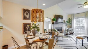 A dining area with a table set for four, a hanging light fixture, and a fireplace in the background. - College Station Gem w/ Pool Access Near University (College Station)