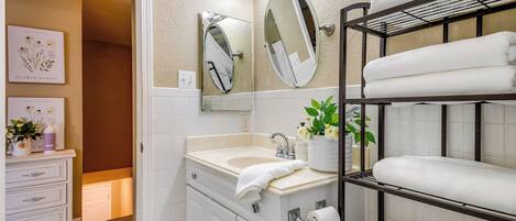 A bathroom with a vanity, a mirror, a sink, a toilet, and a towel rack.