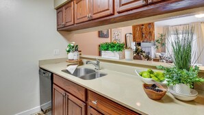 A kitchen with wooden cabinets, a stainless steel sink, and various kitchen items on the counter. - College Station Gem w/ Pool Access Near University (College Station)