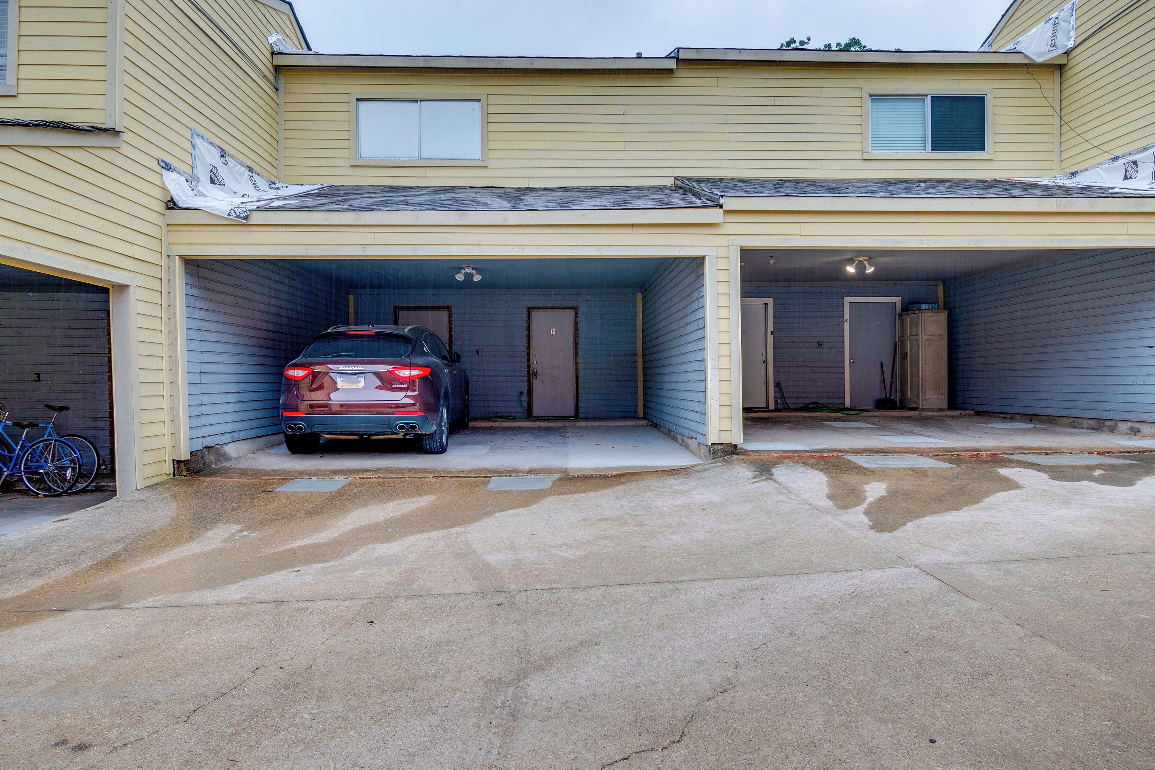 A two-story building with two attached garages, one of which contains a red car.