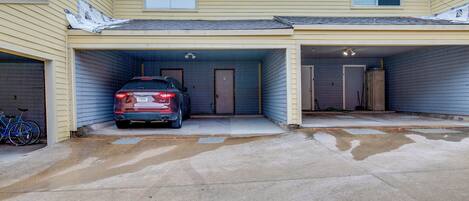 A two-story building with two attached garages, one of which contains a red car.