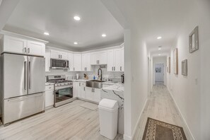 A modern kitchen with white cabinets, stainless steel appliances, and a marble backsplash.